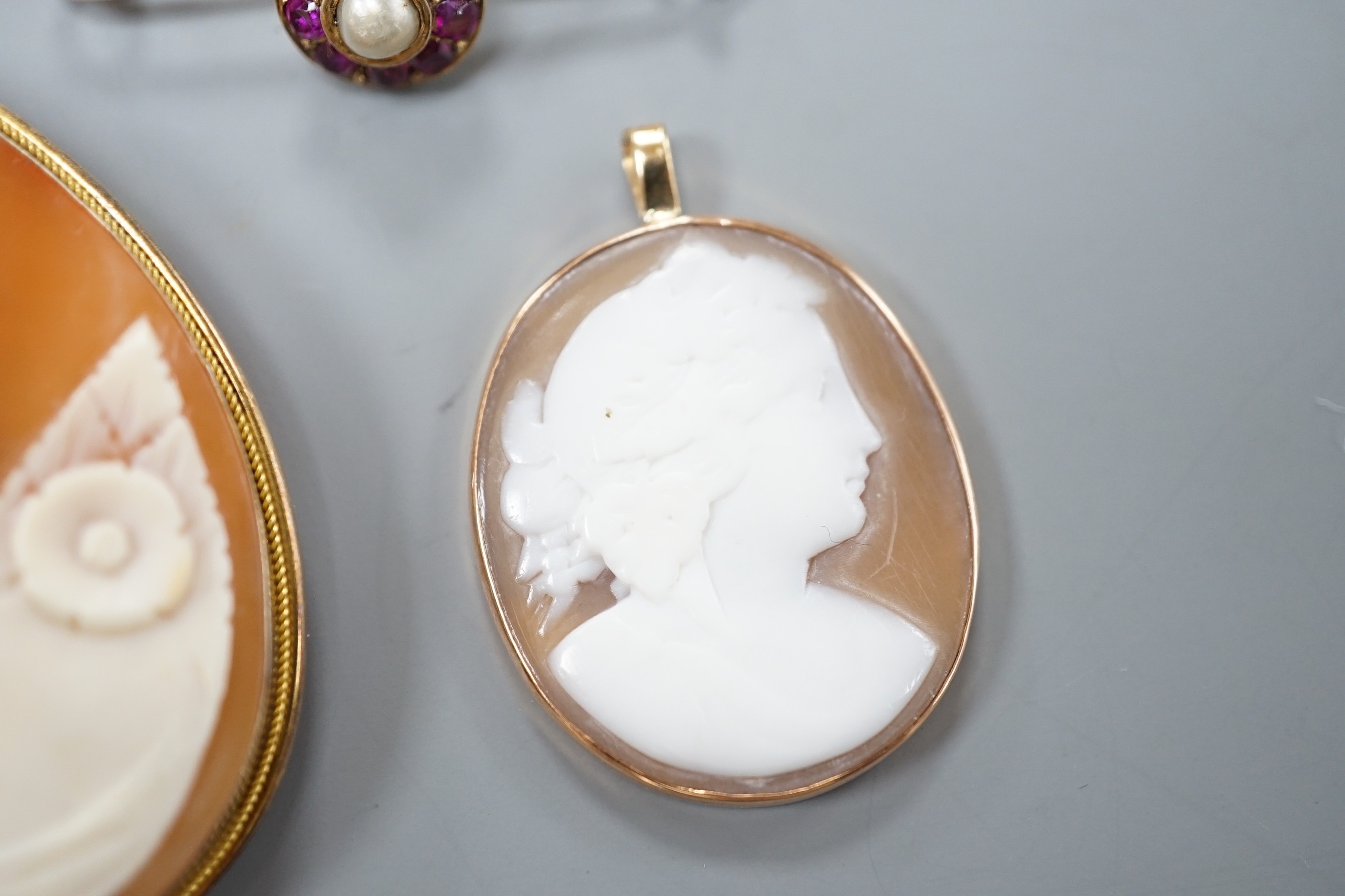 A 9ct mounted oval cameo shell pendant, 36mm, a similar gilt white metal mounted brooch and a yellow metal, ruby and cultured pearl cluster set bar brooch(converted).